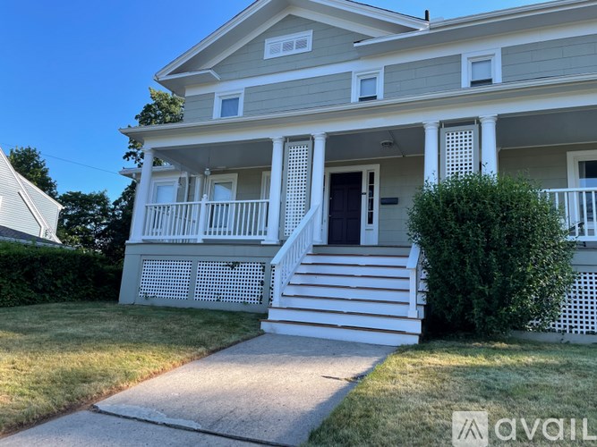 A two-story house with a front porch and stairs leading to the door.