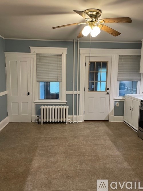 A room with a ceiling fan and a radiator on the floor.