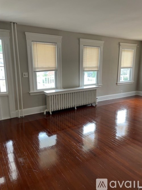A room with wooden floors and a window with blinds.