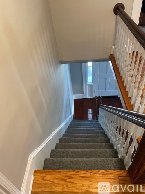 A staircase with a wooden handrail and a carpeted runner.