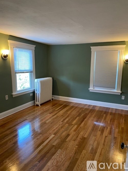 A room with wooden floors and a window with blinds.