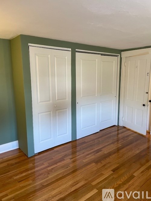 Three white doors in a room with wooden floors.