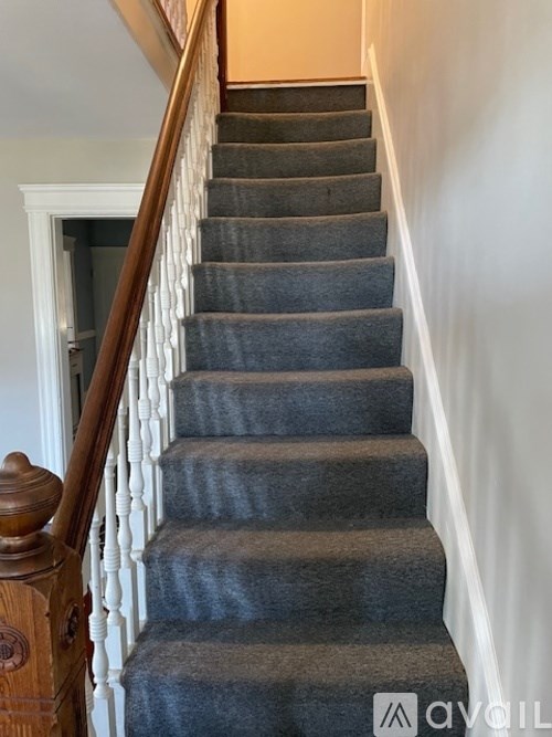 A staircase with a carpeted runner and wooden balusters.
