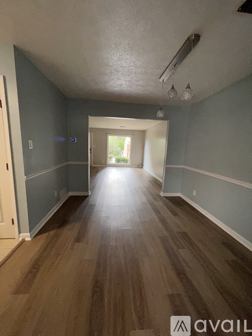 A long hallway with wood floors and a door at the end.