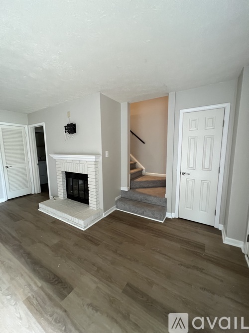 A living room with a fireplace and wooden floors.