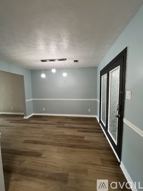 A room with wooden flooring and a door on the right side.