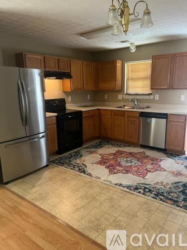 A kitchen with wooden cabinets and a rug on the floor.