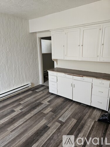 A kitchen with white cabinets and a wooden floor.