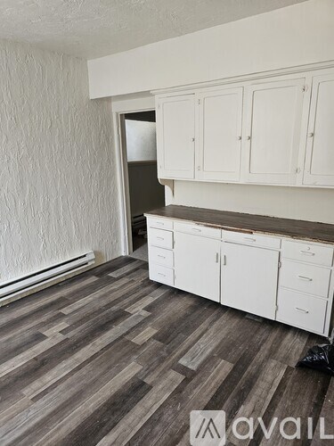 A kitchen with white cabinets and a wooden floor.