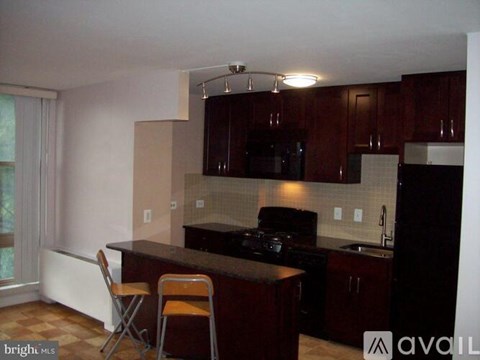 A kitchen with dark wood cabinets and a black stove top oven.