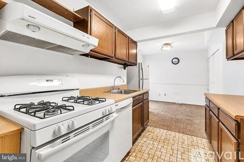A kitchen with a white stove and wooden cabinets.