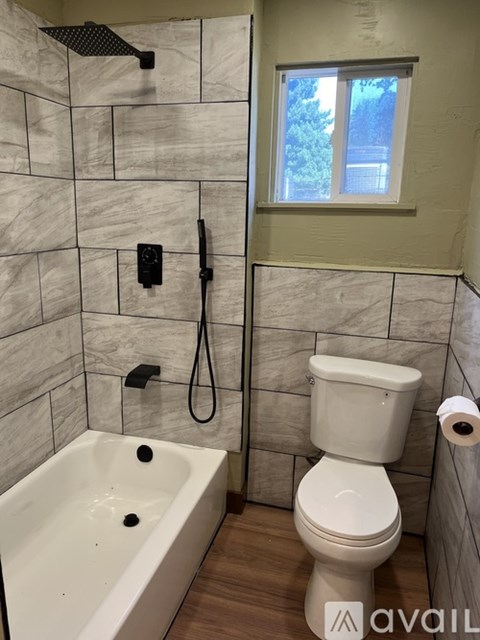 A bathroom with a tub, toilet and window.