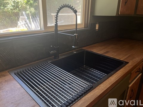 A kitchen sink with a faucet and a window in the background.