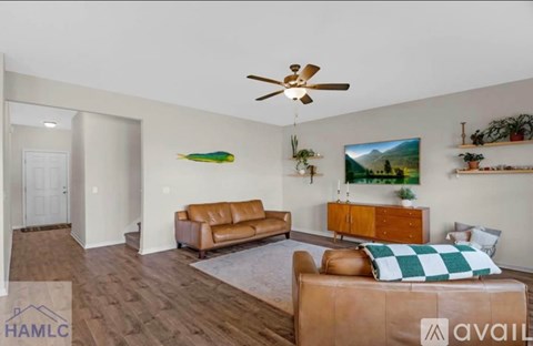 A living room with a brown couch and a ceiling fan.