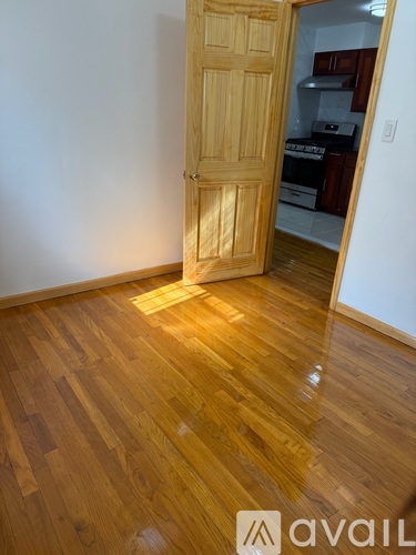 A room with a wooden floor and a wooden door leading to another room.