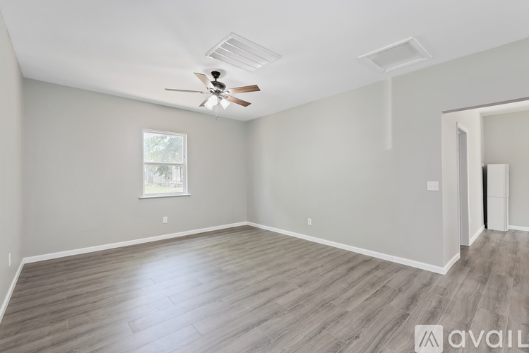 A spacious room with a ceiling fan and a door on the right side.