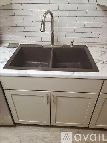 A kitchen sink with a faucet and a countertop with a marble finish.