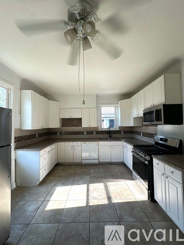 A kitchen with white cabinets and a fan on the ceiling.