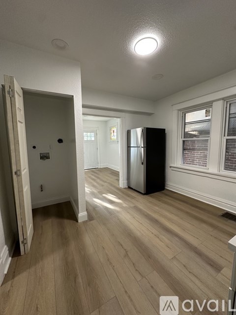A kitchen with a refrigerator and a door open to a hallway.