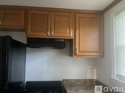 A kitchen with wooden cabinets and a black refrigerator.