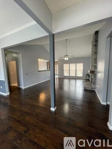 A spacious room with wooden floors and a large window.