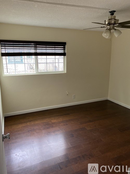 A room with a ceiling fan and a window with blinds.