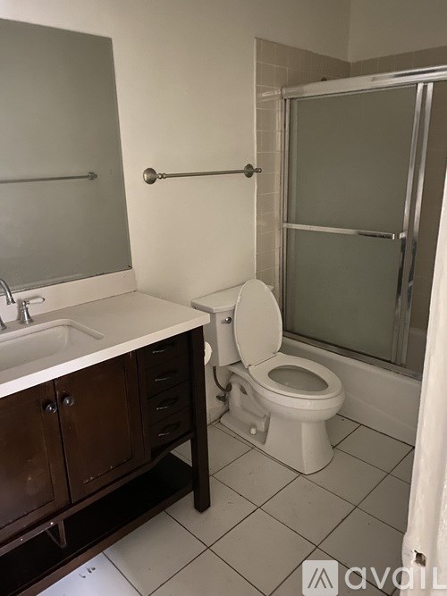 A white toilet sits in a bathroom next to a sink and a shower.