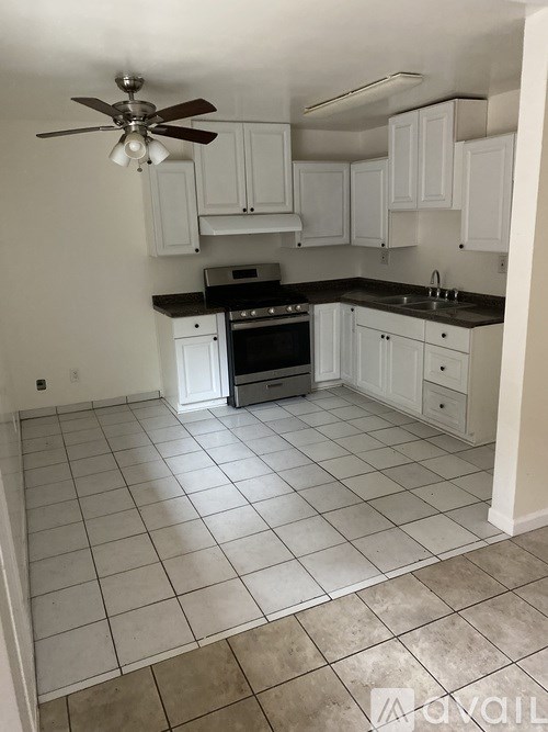 A kitchen with white cabinets and a black stove top oven.