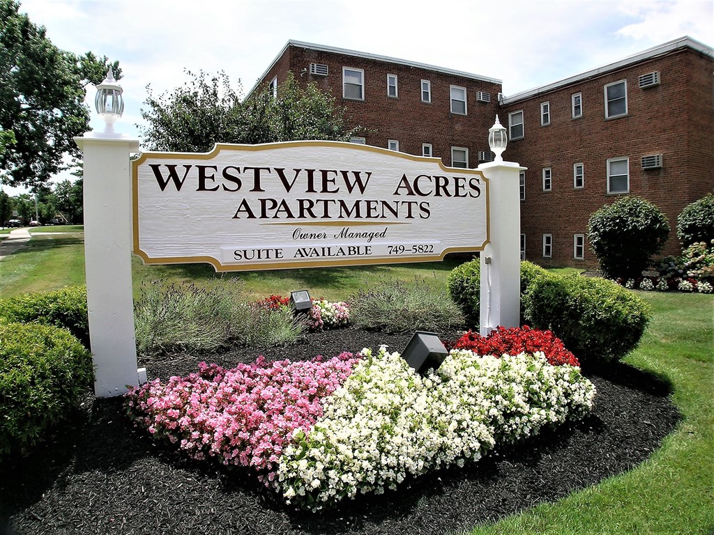 A sign for Westview Acres Apartments with a flower bed in front.