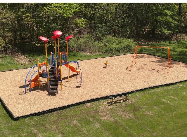 A playground with a slide, swings, and a sandbox.