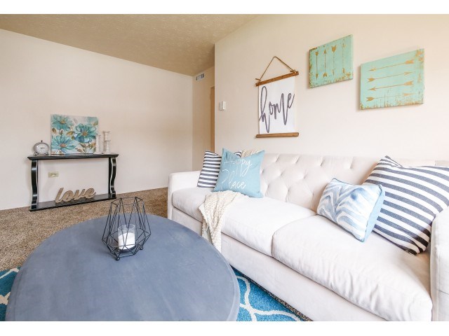 A living room with a white couch and a blue ottoman.