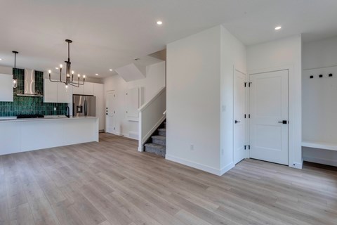 A spacious room with wooden flooring and a staircase.