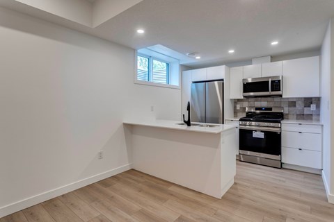 A kitchen with white cabinets and a wooden floor.