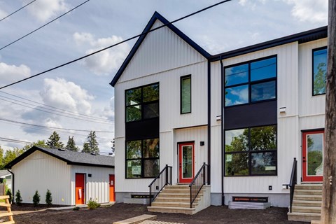 A modern house with a red door and a black roof.