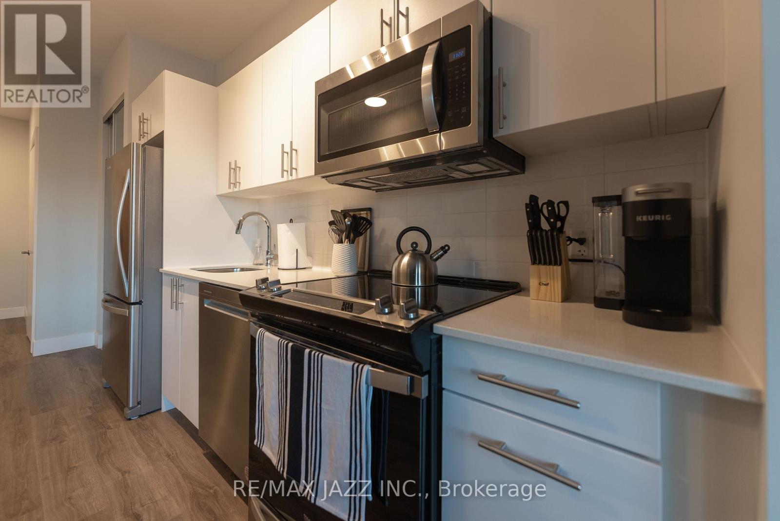 A modern kitchen with a black stove top oven and white cabinets.
