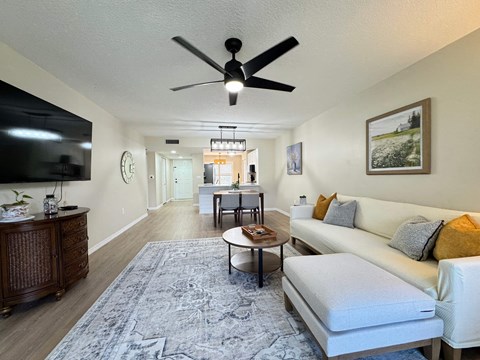A living room with a white couch and a ceiling fan.