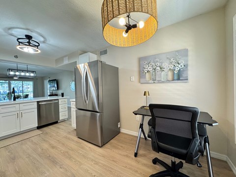 A kitchen with a refrigerator, a table and a chair.