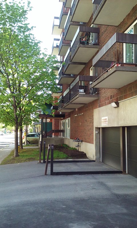A tree is next to a building with a balcony.