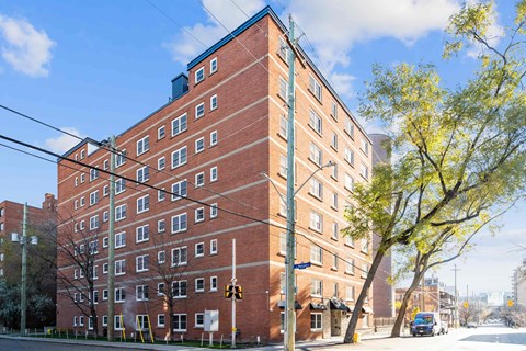 A red brick building with a green tree in front.