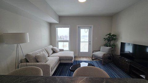 A living room with a couch, chairs, and a television.