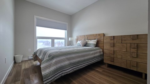 A bedroom with a bed, nightstand, and window.
