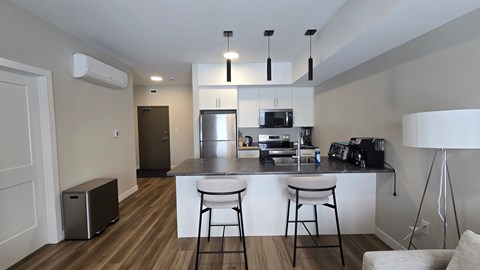 A kitchen with a white counter and bar stools.