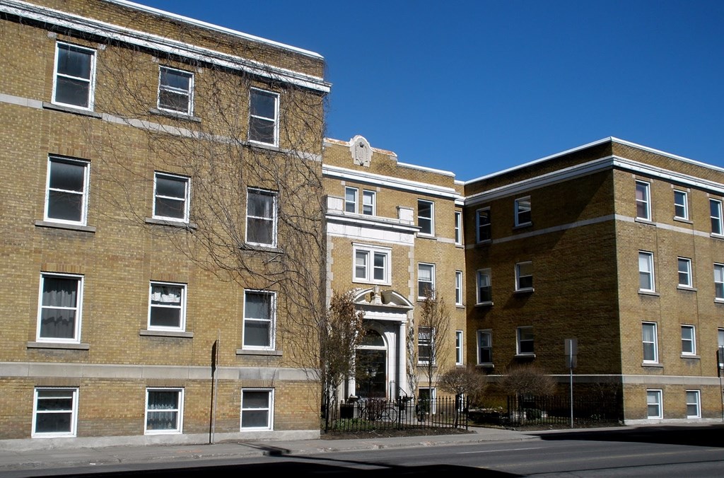 A large brick building with a black fence in front.