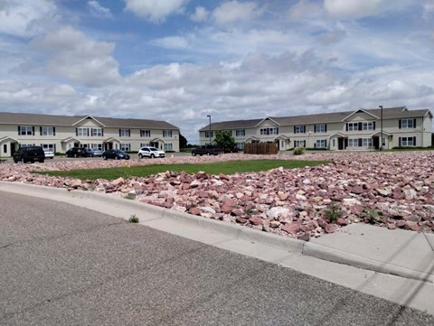 A large pile of red bricks sits in the foreground of a residential street.