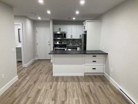 A kitchen with a black countertop and white cabinets.