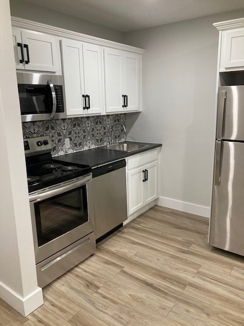 A kitchen with white cabinets and a stainless steel refrigerator.