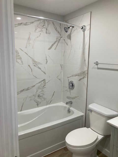 A white toilet sits next to a bathtub in a bathroom with marble tile walls.