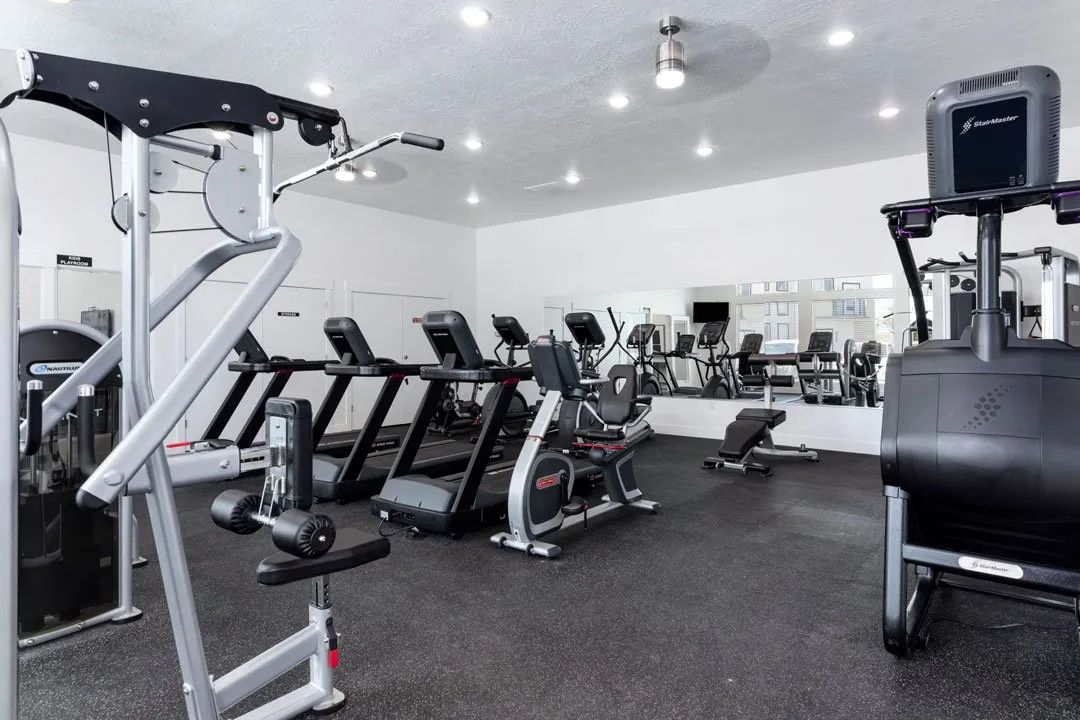 A gym with a variety of equipment including treadmills, weights, and exercise machines.