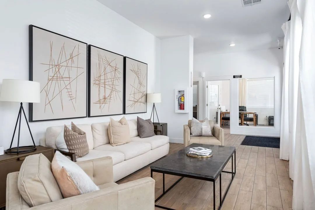 A living room with a beige couch, a coffee table, and a large abstract painting on the wall.