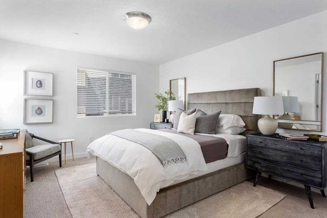 A bedroom with a large bed, a nightstand, and a chair.